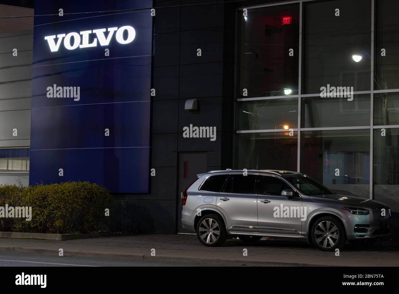 Volvo XC90 parcheggiato davanti a un concessionario Volvo nel centro di Toronto. Il logo di testo Volvo sull'edificio si illumina di notte. Foto Stock