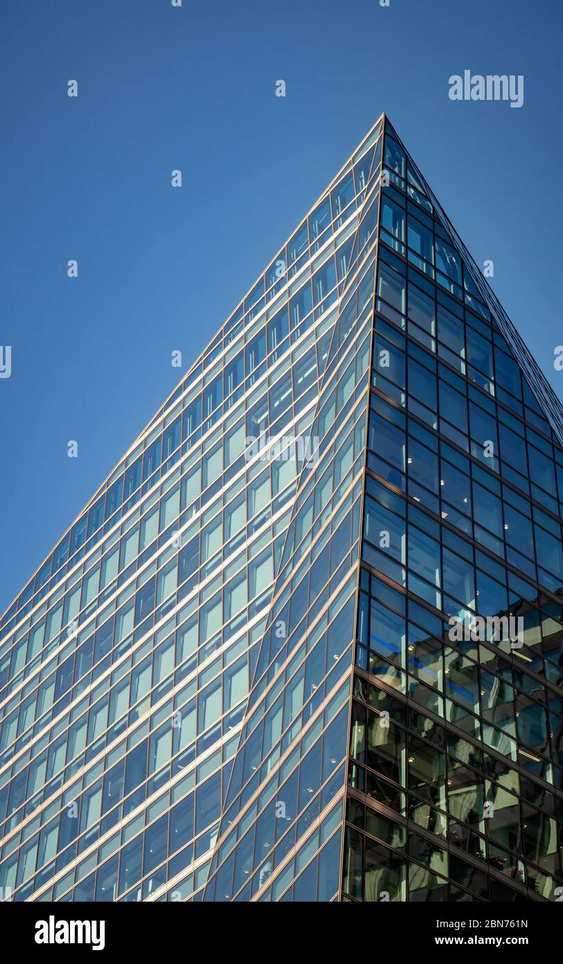 Architettura angolare. Una vista ad angolo basso di un edificio d'ufficio astratto e contemporaneo ad angolo nel centro di Londra. Foto Stock