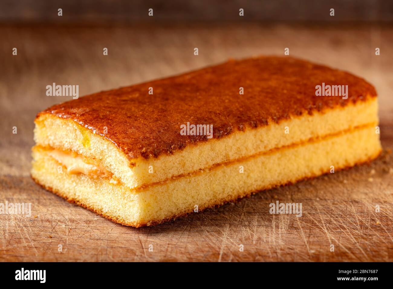 Pan di Spagna ripieno di frutta e crema di vaniglia su tavolo di legno Foto Stock