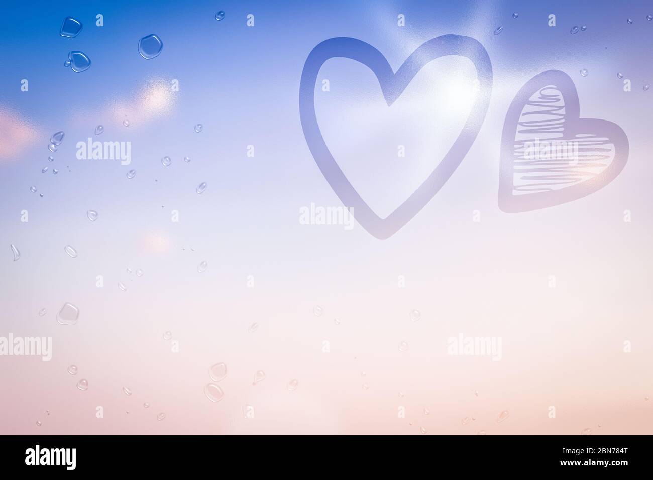 Due cuori disegnati su un vetro bagnato Foto Stock