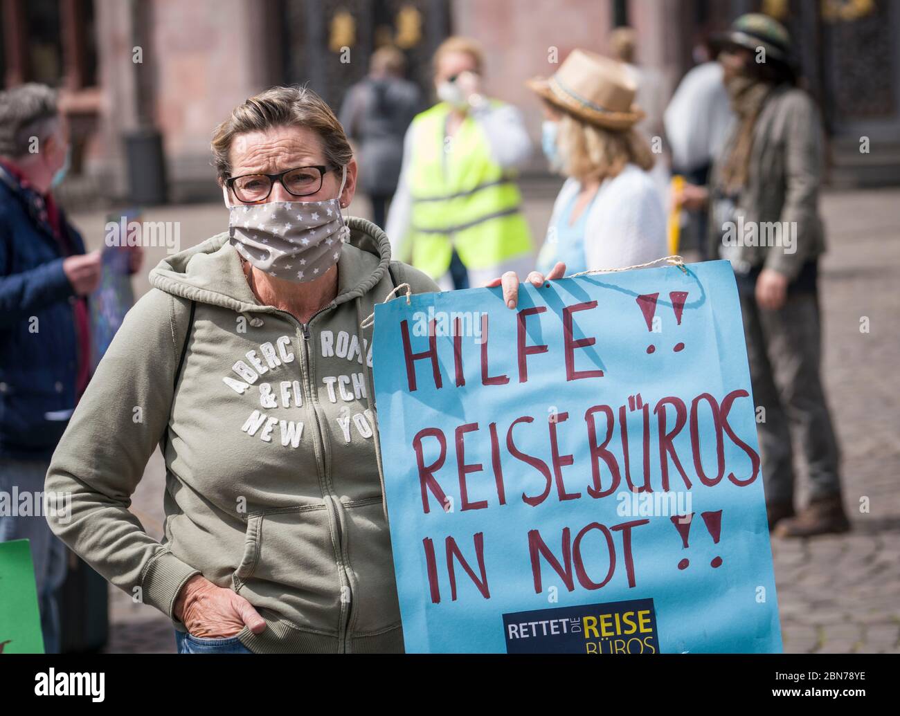 13 maggio 2020, Hessen, Francoforte sul meno: Una donna con un poster che dice 'Aiuto! Agenzie di viaggio nel bisogno' si trova di fronte al romano durante una dimostrazione da parte dei proprietari di agenzie di viaggio e tour operator di medie dimensioni. I dimostranti chiedono un fondo federale speciale per la gestione dei rimborsi per i viaggi annullati. Ciò è per assicurare i lavori nelle agenzie di corsa e nei tour operator. Foto: Frank Rumpenhorst/dpa Foto Stock