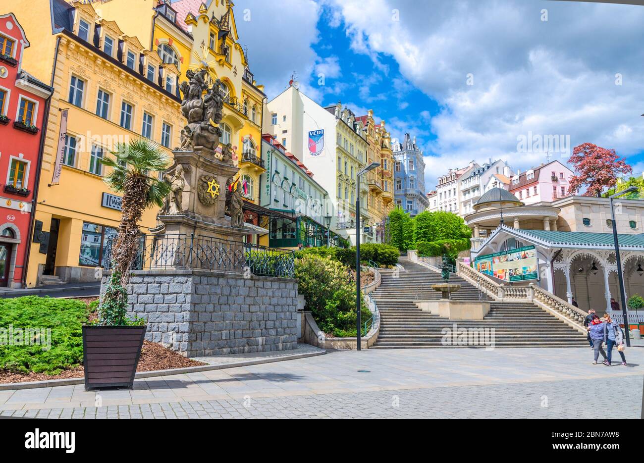 Karlovy Vary, Repubblica Ceca, 10 maggio 2019: Colonna della Santissima Trinità vicino al mercato Colonnade Trzni kolonada colonnato in legno con sorgenti termali calde nel centro storico della città di Carlsbad, Boemia Occidentale Foto Stock