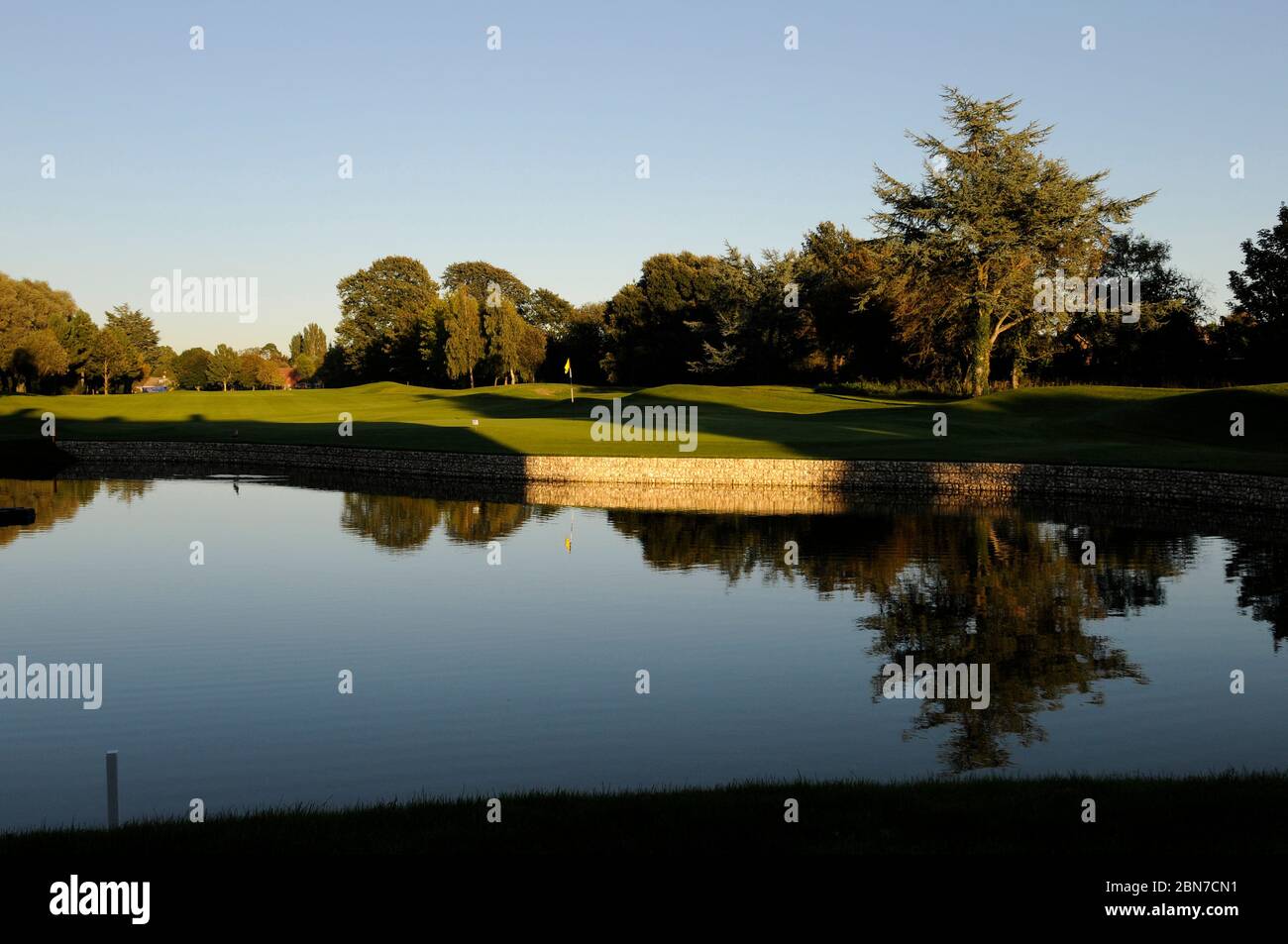 Vista sul lago al 18th Green e Fairway con ombre; Ham Manor Golf Club, Angmering, Sussex, Inghilterra Foto Stock
