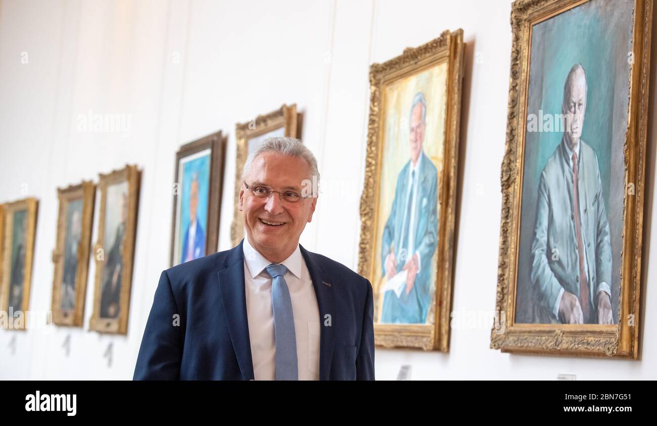 Monaco, Germania. 13 maggio 2020. Joachim Herrmann (CSU), Ministro degli interni della Baviera, passa vari ritratti di ex Presidenti del parlamento bavarese nell'anticamera durante la sessione del parlamento bavarese. Tra gli argomenti della sessione del 13.05.2020 figurano una modifica della legge sull'uso dei contributi di ricorso per la salute per i trasporti pubblici e gli attuali controlli alle frontiere in seguito alla pandemia di Corona. Credit: Peter Kneffel/dpa/Alamy Live News Foto Stock