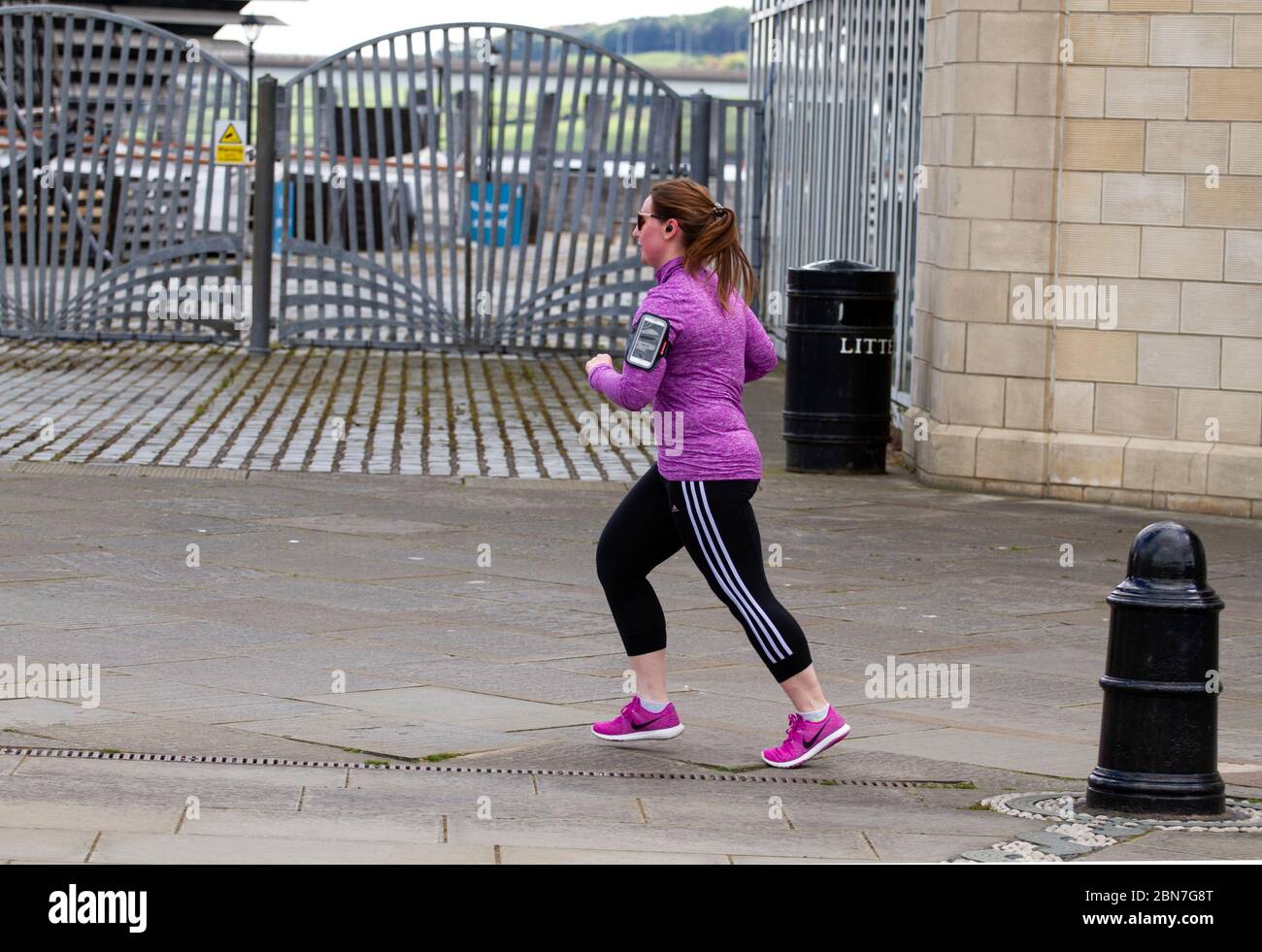 Dundee, Tayside, Scozia, Regno Unito. 13 maggio 2020. Tempo: Nuvoloso con alcuni intervalli soleggiati attraverso Tayside in Scozia con temperatura massima 14°C. Il primo Ministro Nicola Sturgeon ha annunciato nuove indicazioni che raccomandano al popolo scozzese di rendere obbligatorio indossare maschere in pubblico. Nonostante le normative sulla maschera facciale, i residenti locali si allenano alla luce lungo il lungomare di Dundee. Una giovane femmina trascorre una giornata facendo jogging lungo il Discovery Point accanto al V&A Design Museum e alla nave da scoperta RRS. Credit: Dundee Photographics/Alamy Live News Foto Stock