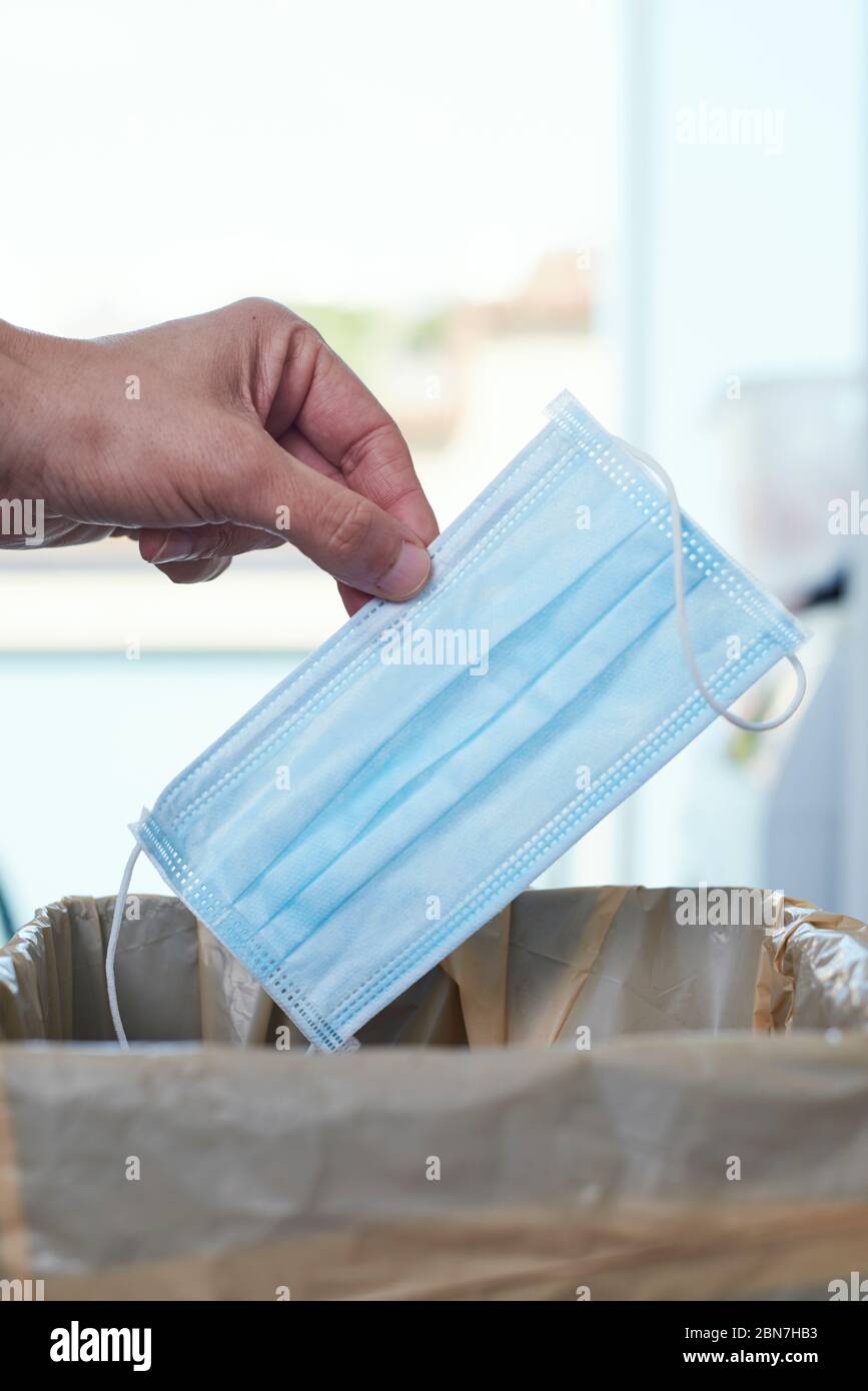 primo piano di un uomo che lancia una maschera chirurgica al cestino può Foto Stock