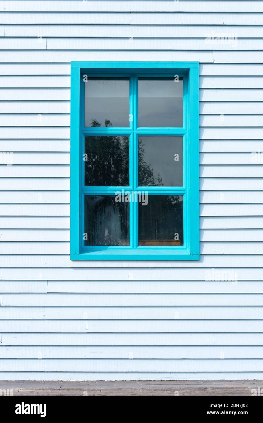 Lato di un edificio clapboard con una finestra, dipinto di blu. Foto Stock