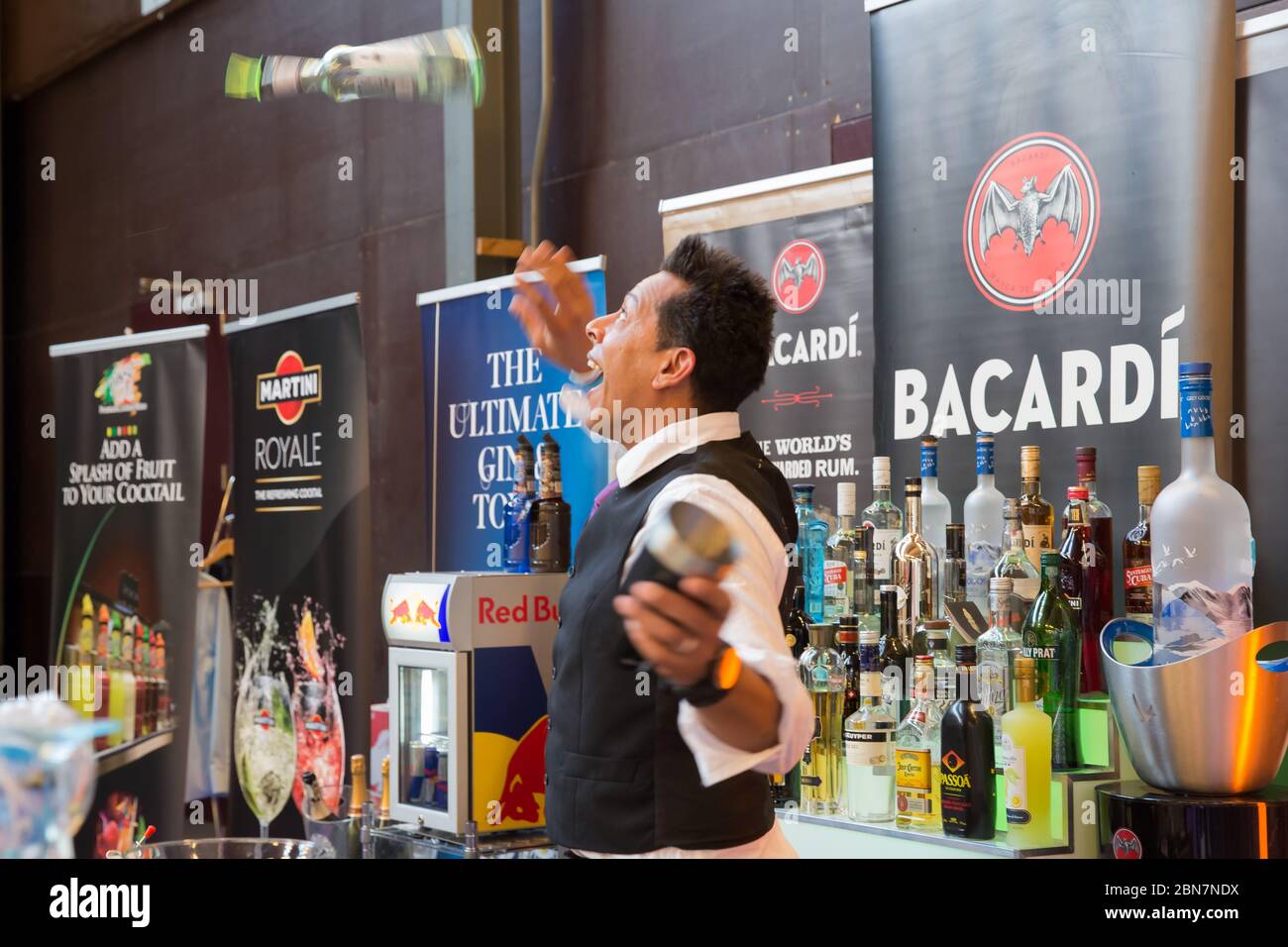 Barman che lancia una bottiglia di alcol nel cocktail Air Making Foto Stock