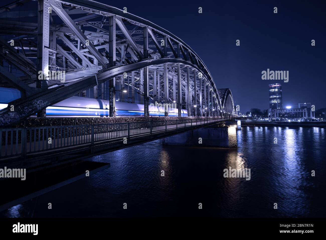 Treno a cavallo sul ponte alla stazione centrale di Colonia di notte Foto Stock