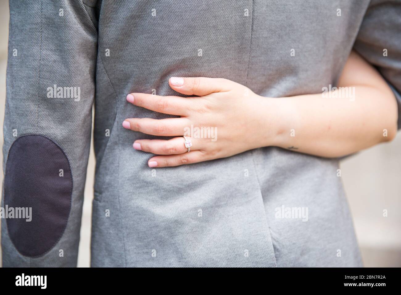 Uomo e donna si stringe l'un l'altro dalla vita mostrando l'anello di nozze Foto Stock