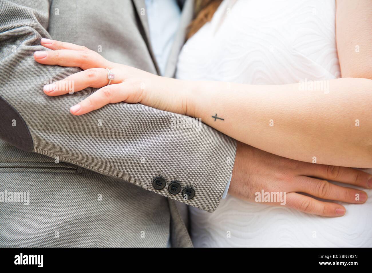 Uomo e donna si stringe l'un l'altro dalla vita mostrando l'anello di nozze Foto Stock