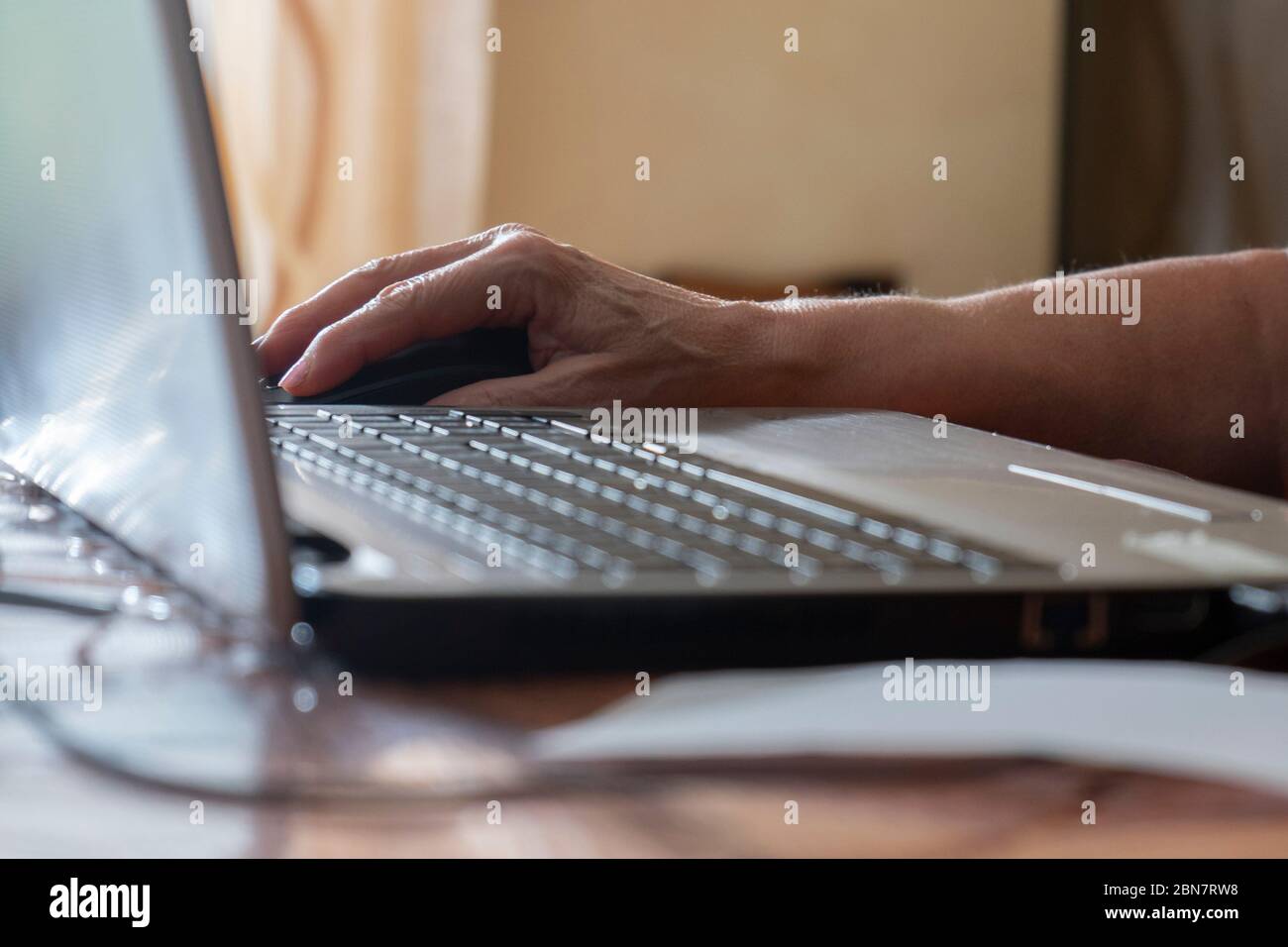 Mano di donna anziana che usa il notebook. Mettere a fuoco sulla mano. Concetto di utilizzo del computer da parte degli anziani. Foto Stock