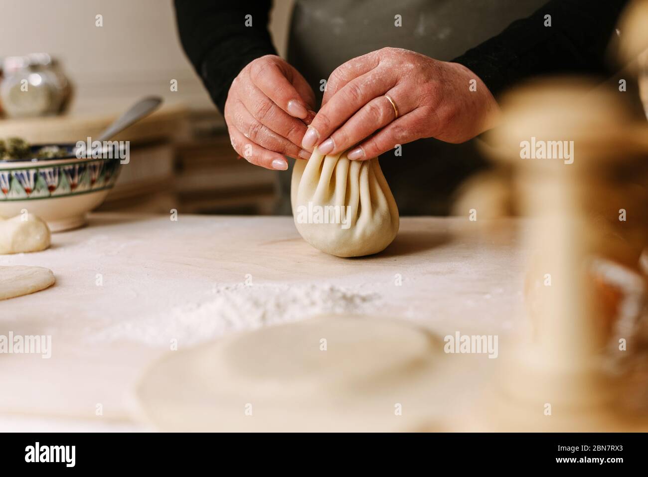 Cottura a processo. Donna che fa khinkali per la sua famiglia primo piano. Preparazione tradizionale georgiano pasto di pasta e carne in cucina. Cucina nazionale, concetto di processo di cottura. Foto Stock