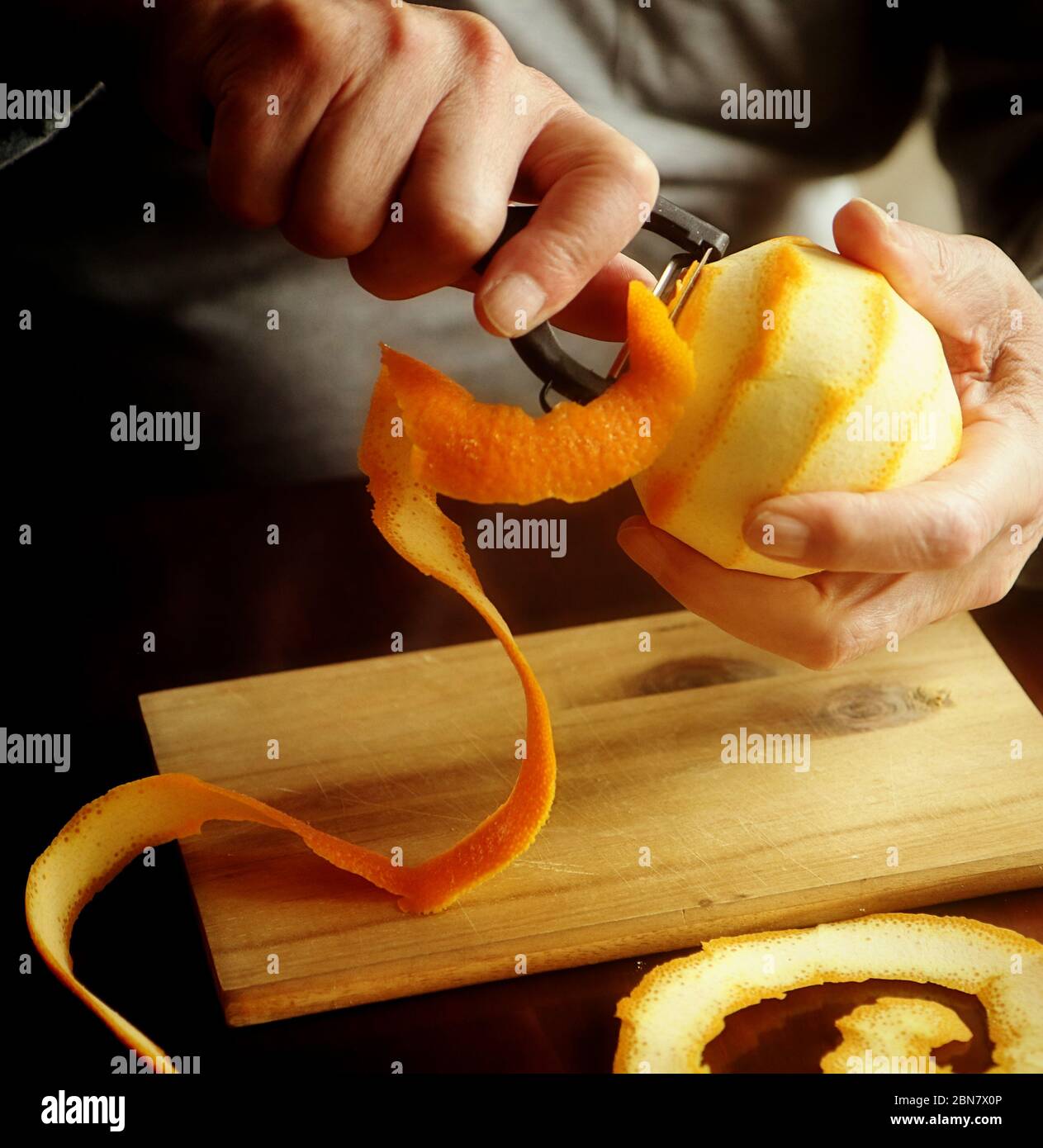Preparazione della marmellata d'arancia: Rimozione della scorza d'arancia con un pelatore vegetale affilato, da aggiungere alla marmellata Foto Stock