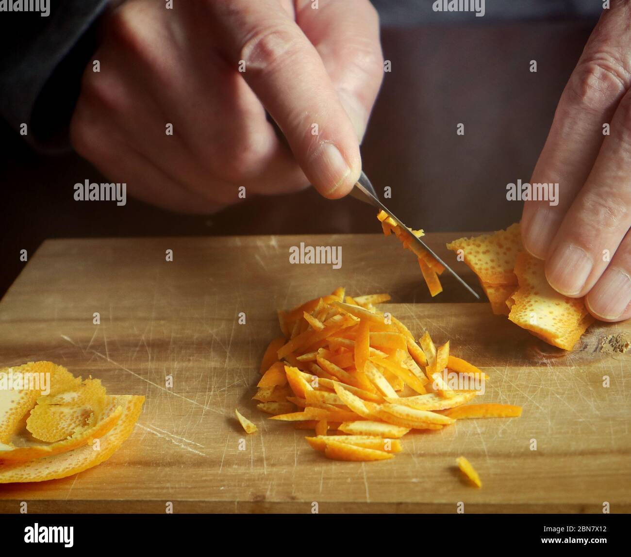 Preparazione della marmellata d'arancia: Tagliando con un coltello affilato la scorza d'arancia in piccole fette per aggiungerla alla conserve fatta in casa Foto Stock