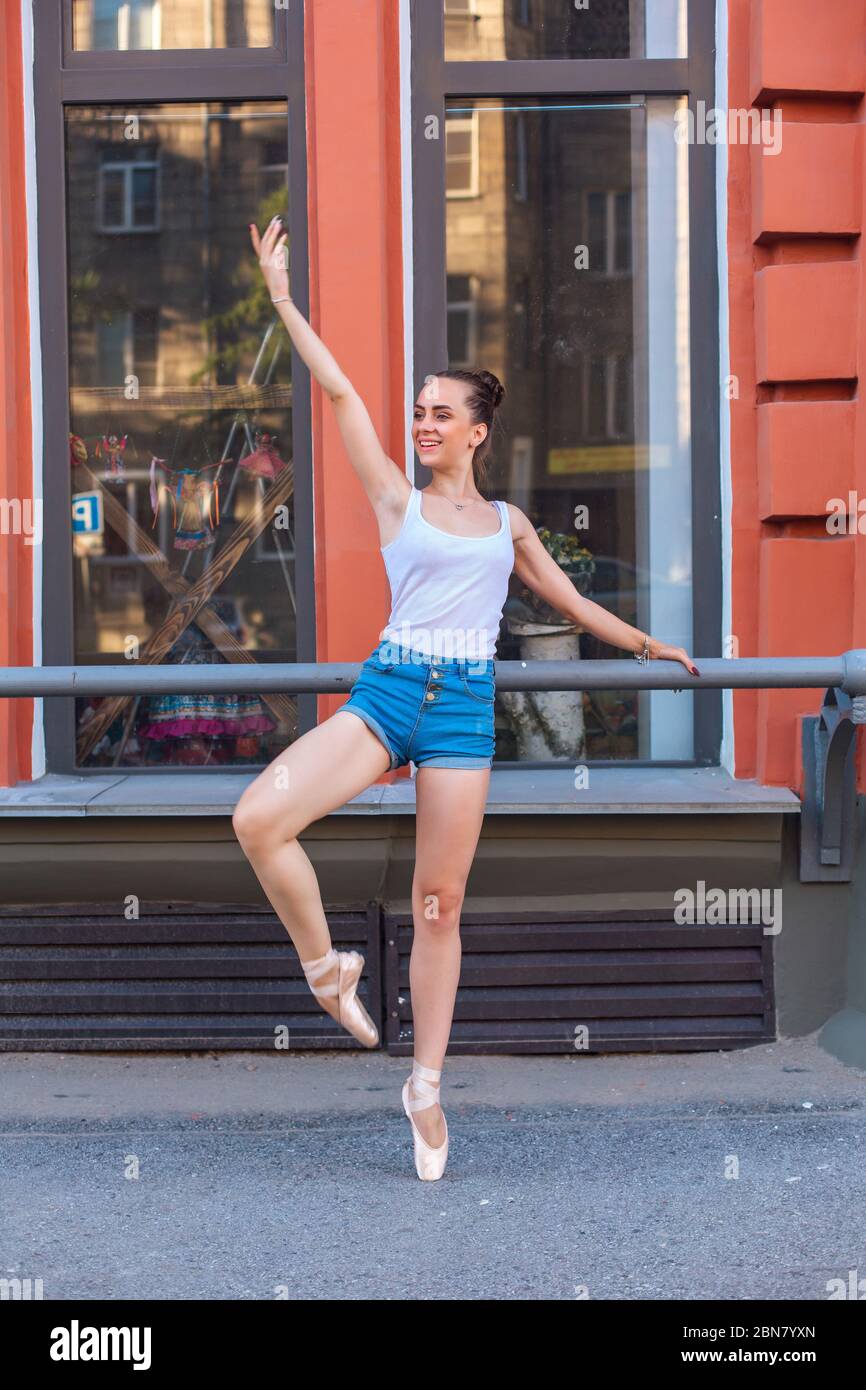 Giovane ballerina in camicia bianca e jeans shorts ballerine in scarpe  pointe su una strada Foto stock - Alamy