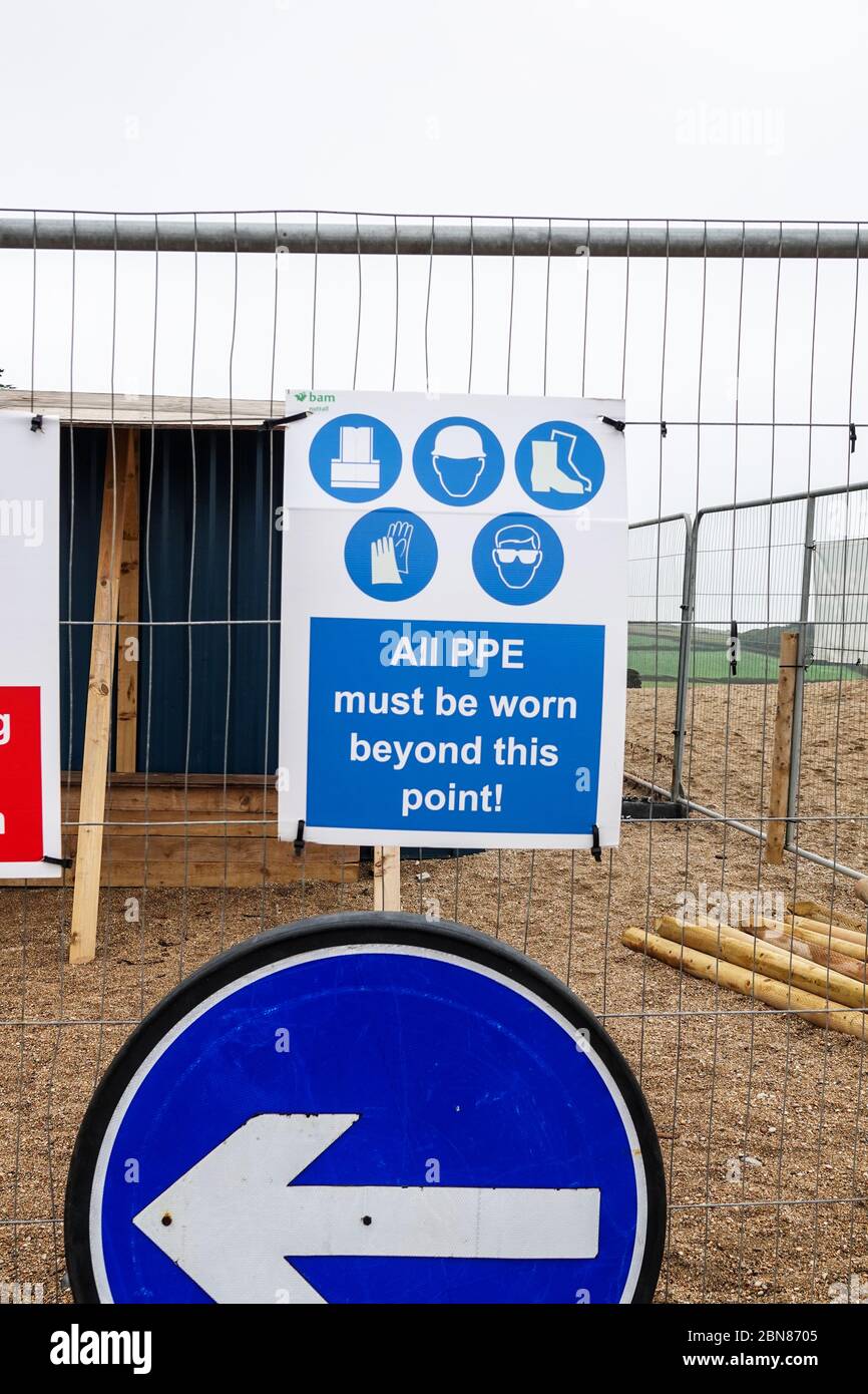 Un cartello su un cantiere che dice che i dispositivi di protezione individuale (DPI) devono essere indossati oltre questo punto, Inghilterra, Regno Unito Foto Stock