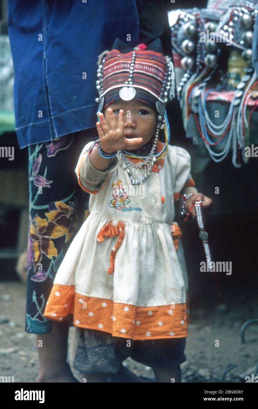 Giovane donna di vendita tailandese da una tribù collina nel nord della Thailandia, offrendo un orologio e mostrando con le dita quanto costa. Foto Stock