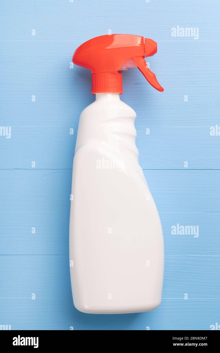 Flacone di spray detergente con custodia bianca senza iscrizioni e dispenser rosso brillante su fondo di legno azzurro. Chiusura prodotto lavaggio a domicilio- Foto Stock