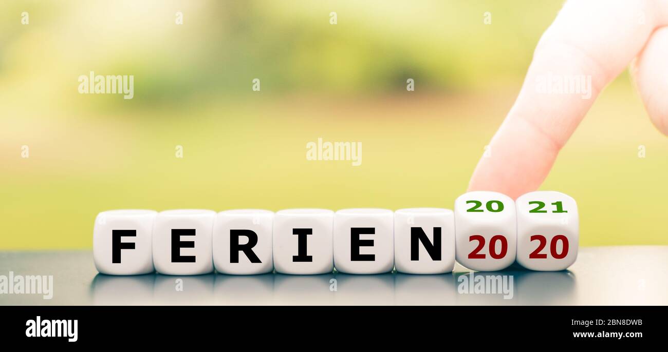 Nessuna vacanza nel 2020 a causa del virus corona. La mano gira dadi e cambia l'espressione tedesca 'Ferien 2020' ('Vacation 2020') in 'Ferien 2021' ('Vaca Foto Stock