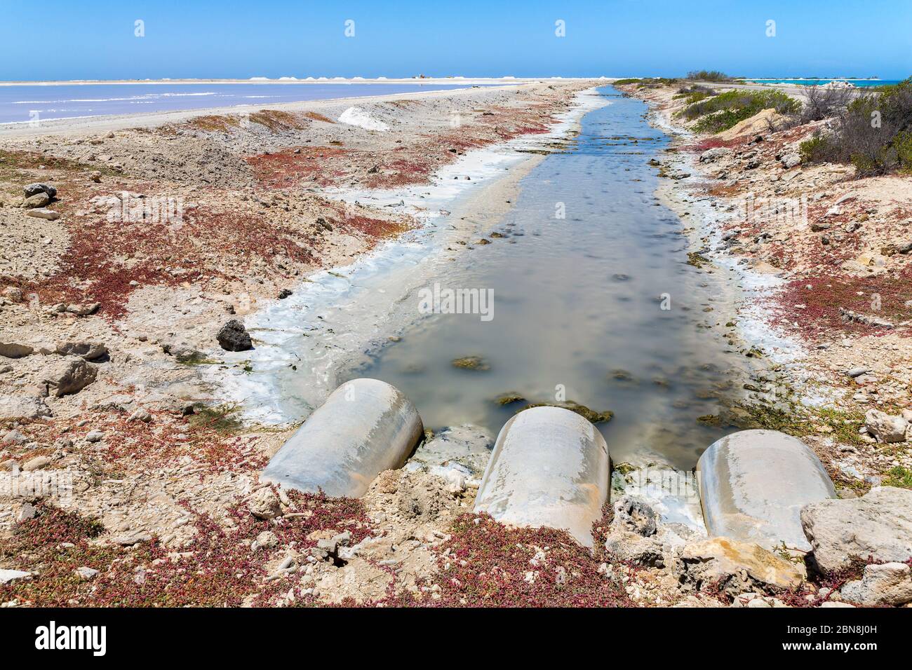 I tubi di scarico scaricano le acque reflue in un flusso per l'industria del sale su Bonaire Foto Stock