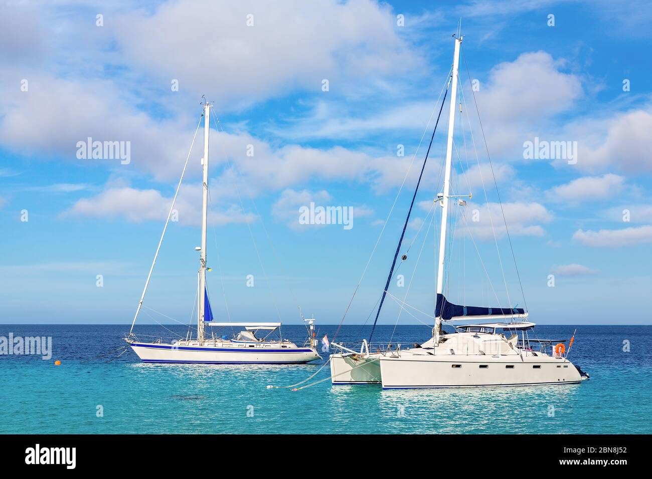 Due barche a vela galleggianti su acque blu vicino alla costa di Bonaire Foto Stock