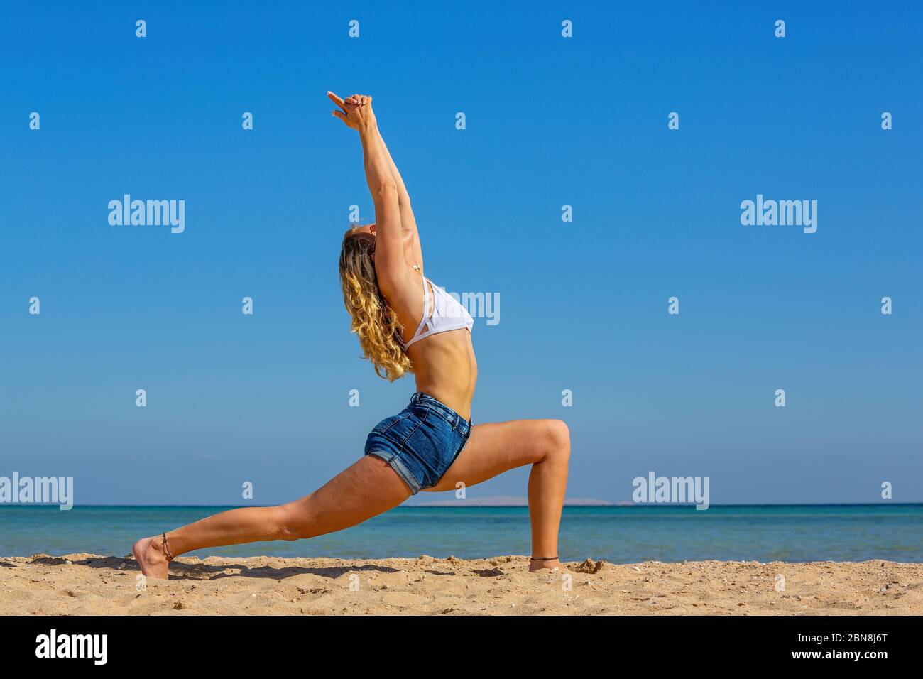 Giovane donna caucasica in posa yoga sulla spiaggia Foto Stock