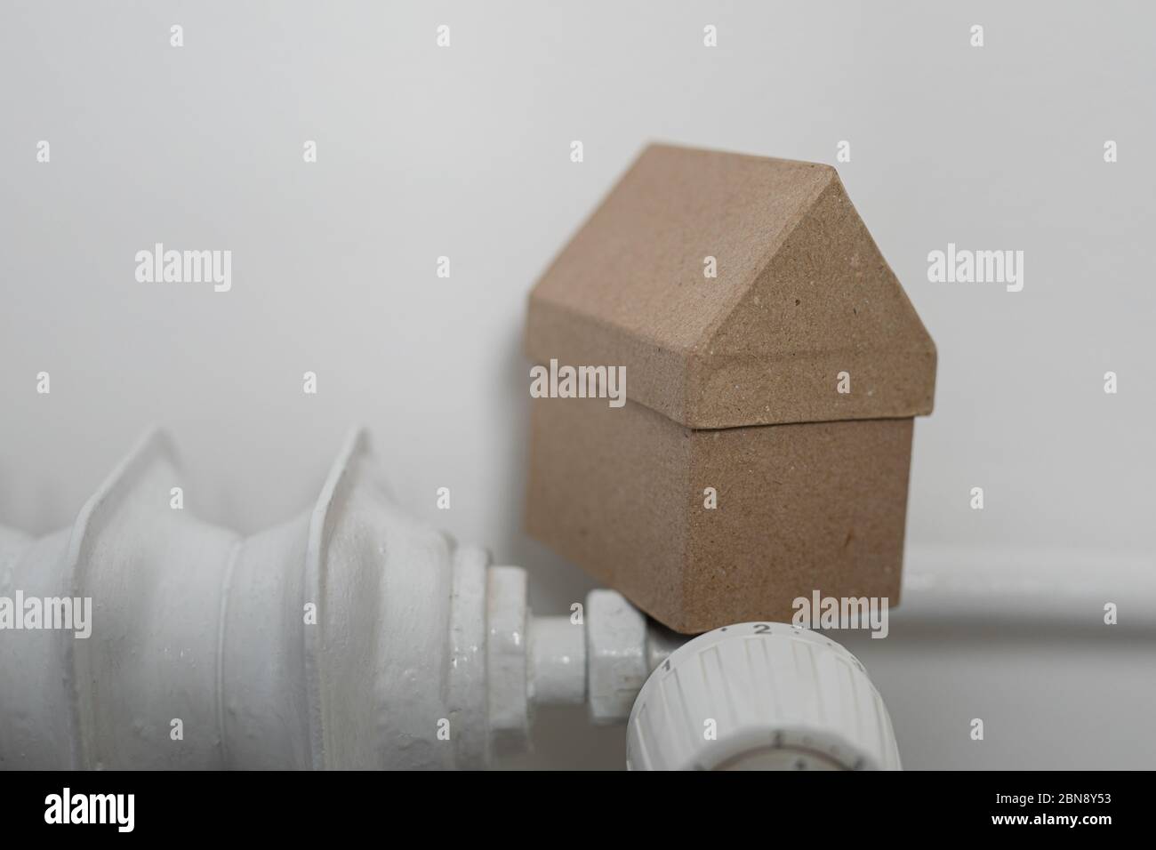 Un riscaldatore con casa su parete bianca Foto Stock