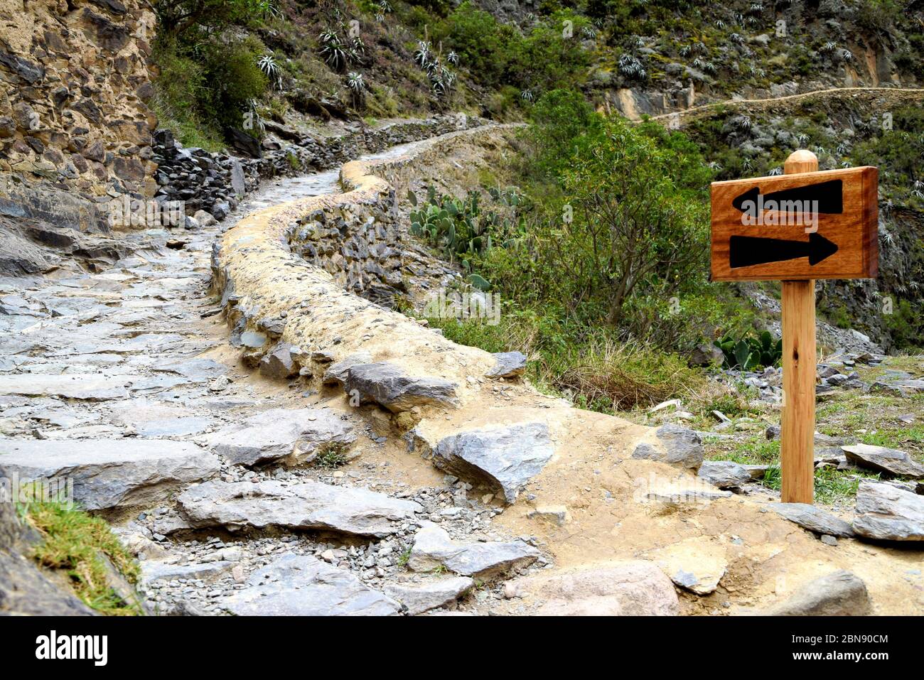 Un cartello con le frecce accanto ad un sentiero in salita. Frecce direzionali che mostrano quali modi andare per i turisti. Foto scattata a Cusco, Perù Foto Stock