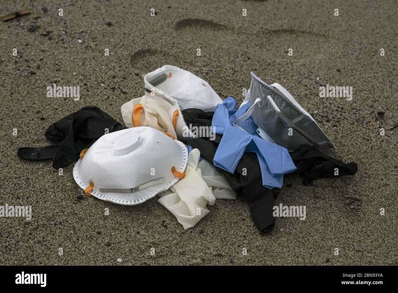 Maschera protettiva da virus e guanti di plastica rifiuti medici sulla costa sabbiosa del mare, malattia da inquinamento da covidi coronavirus Foto Stock