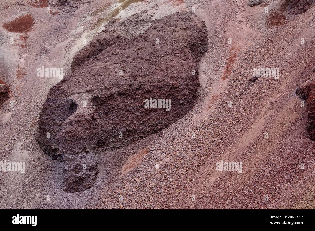 Primo piano di roccia lavica bruna arata, circondata da sabbia lavica rosso-marrone Foto Stock