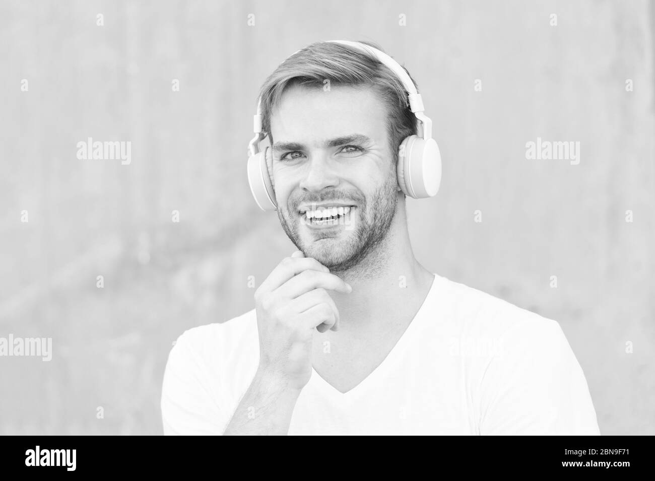 Cuffie adatte per le dimensioni della testa. Felice ragazzo indossare cuffie sfondo grigio. Bel sorriso uomo con cuffie stereo. Cuffie dal design moderno. Nuova tecnologia. Vivi la vita ad alta voce. Foto Stock