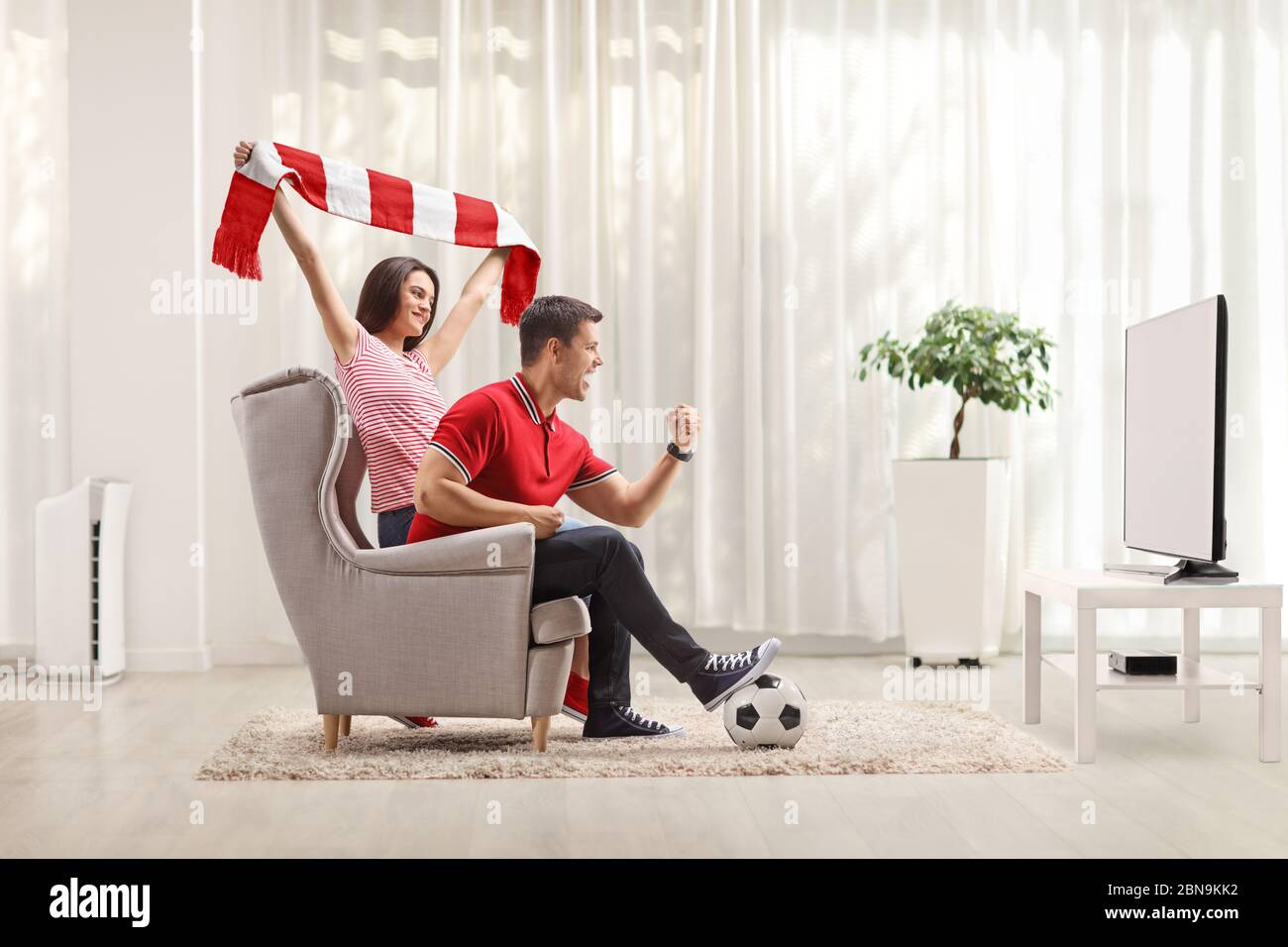 Giovane uomo e donna che guardano la partita di calcio in tv a casa e che si rallegrano Foto Stock