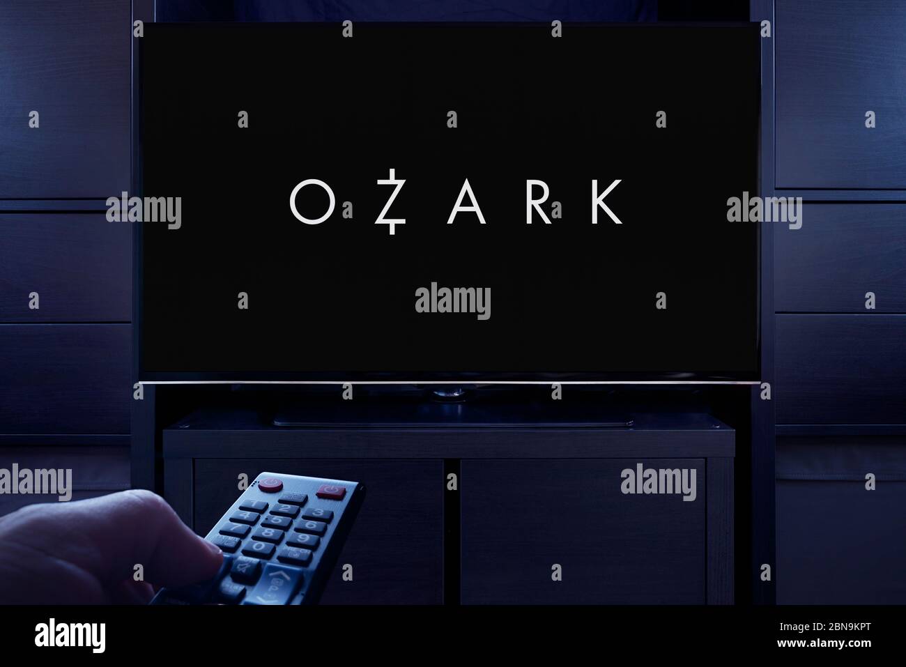 Un uomo punta un telecomando TV verso il televisore che visualizza la schermata principale del titolo di Ozark (solo per uso editoriale). Foto Stock