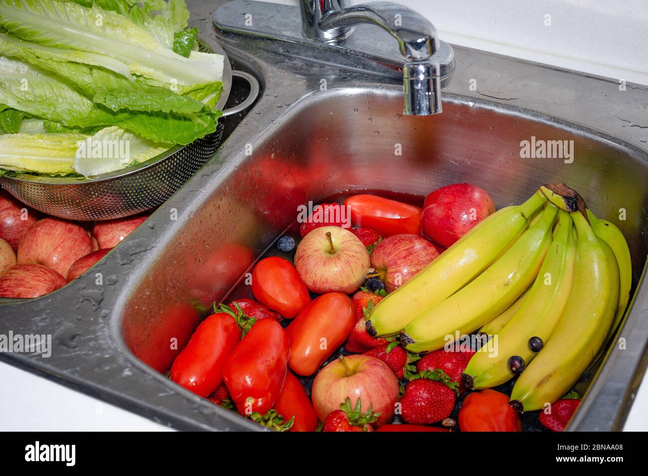 Lavare frutta fresca e verdura acquistato dal negozio di alimentari per rimuovere la possibilità di contaminazione di covid-19 coronavirus Foto Stock