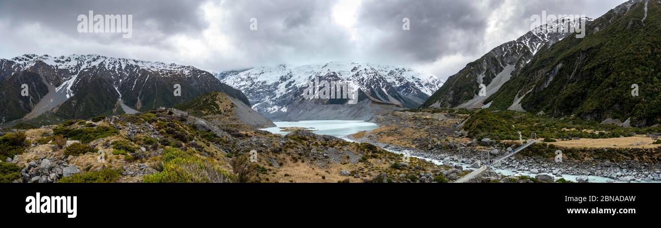 Ponte sospeso sul fiume Hooker, dietro il lago Hooker e il monte Cook, il parco nazionale Mount Cook, le Alpi meridionali, Hooker Valley, Canterbury Region, sud Foto Stock