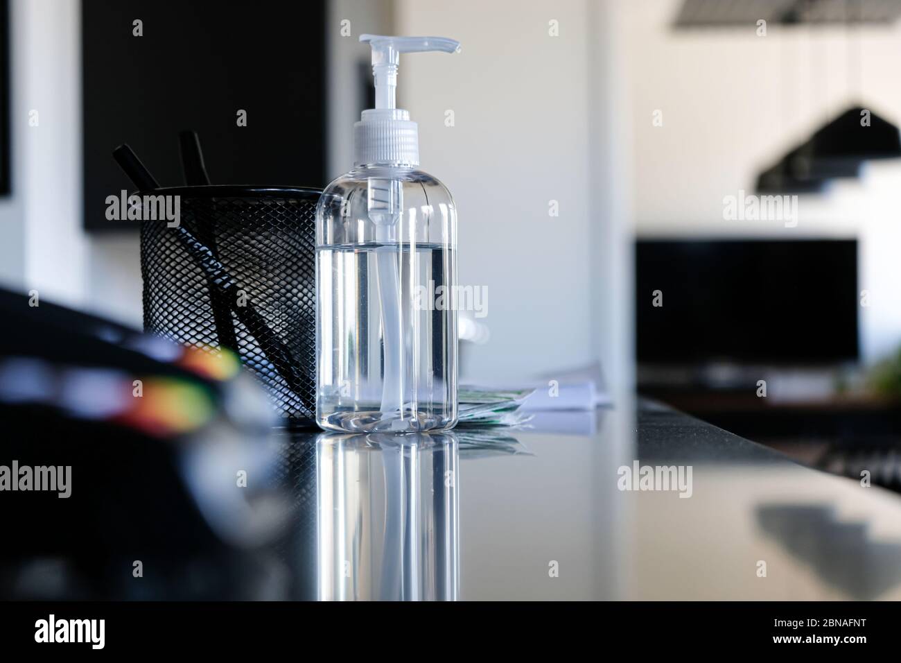 Bottiglia di igienizzatore per mani sul banco della reception dell'ufficio per aiutare a pulire le mani Foto Stock
