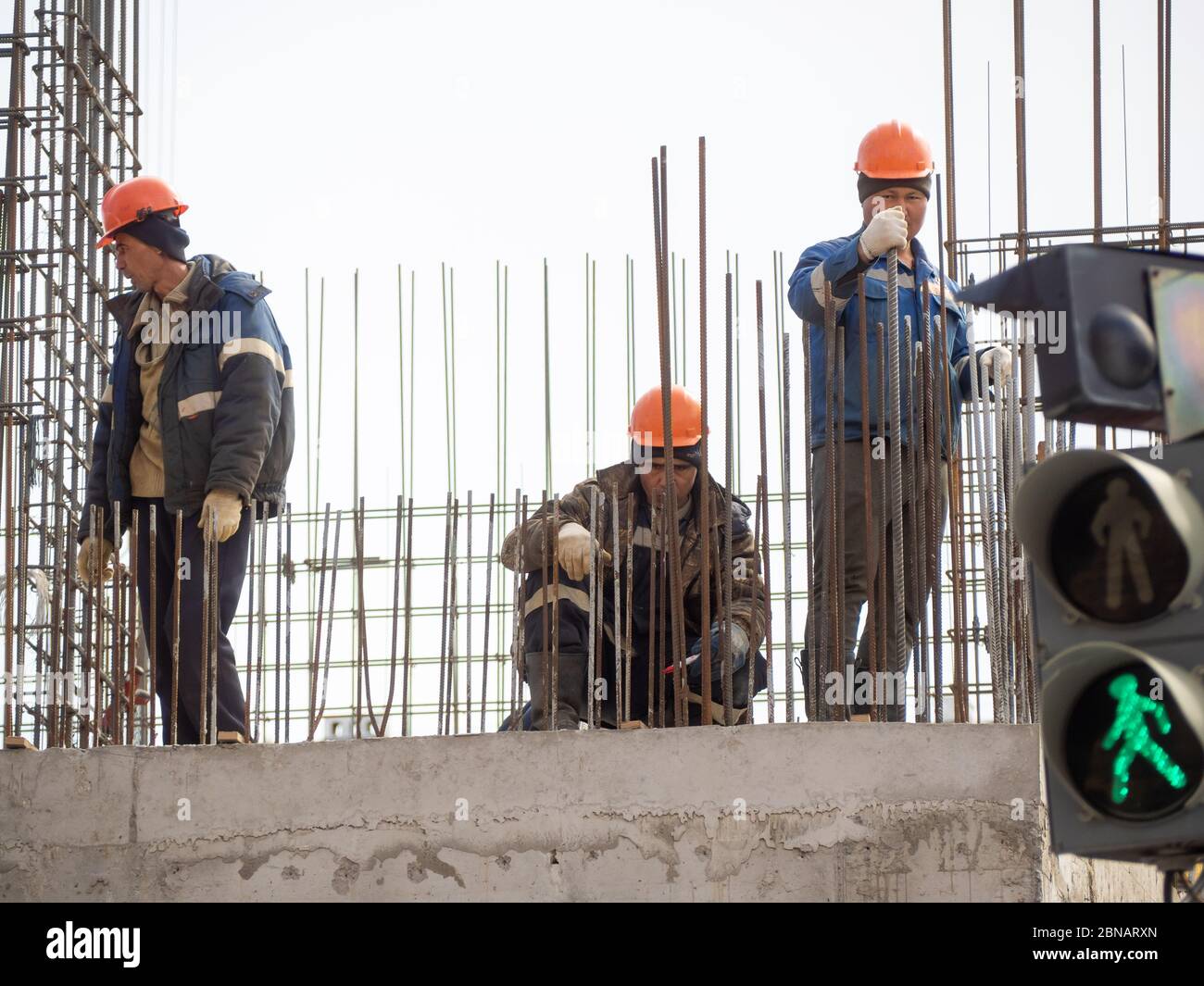 Lavoratori edili che collaborano all'installazione di impianti in un cantiere. Foto Stock