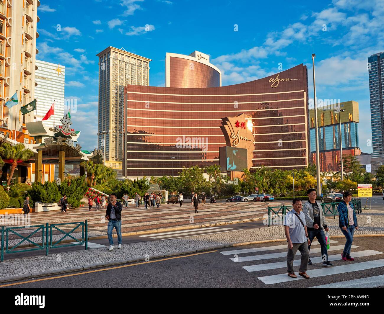 Pedoni che attraversano Avenida do Infante Dom Henrique Street con il Wynn Macau, un hotel di lusso e casinò, sullo sfondo. Macao, Cina. Foto Stock