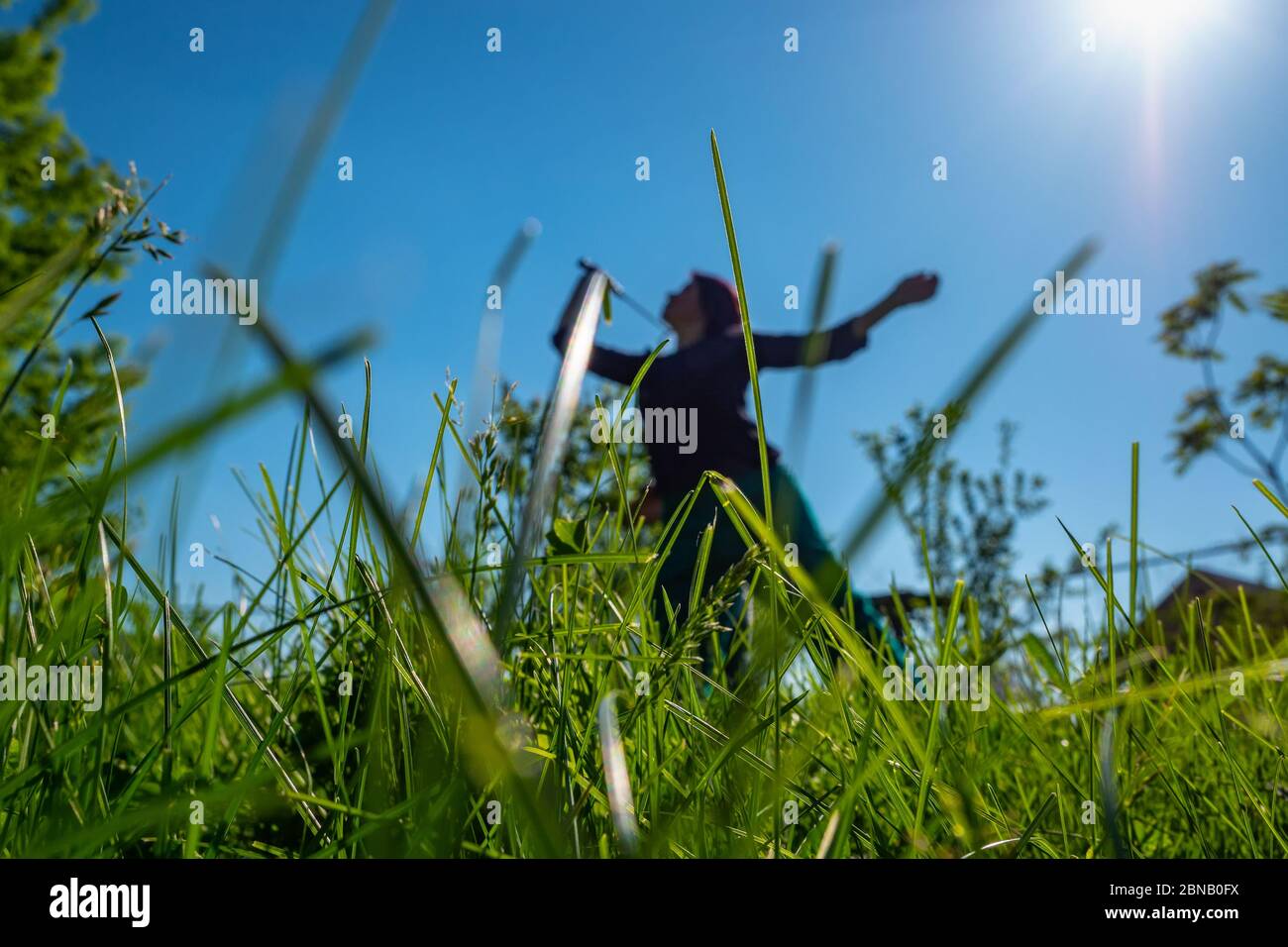 Una ragazza gioca badminton in una compensazione. Passatempo estivo. Mettere a fuoco sull'erba in primo piano. Foto Stock