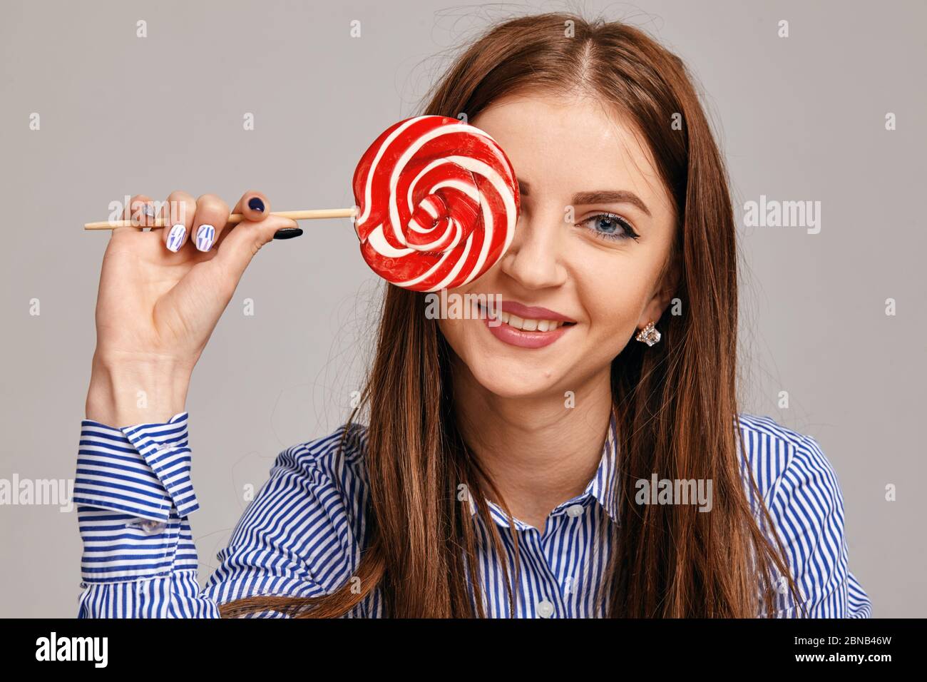 Giovane donna felice con lollipop guardando la macchina fotografica e sorridendo Foto Stock