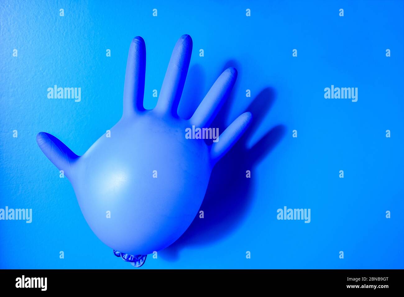 Guanto medico in lattice blu su sfondo blu pastello. Focolaio minimo di coronavirus. Concetto di panico, spazio di copia Foto Stock