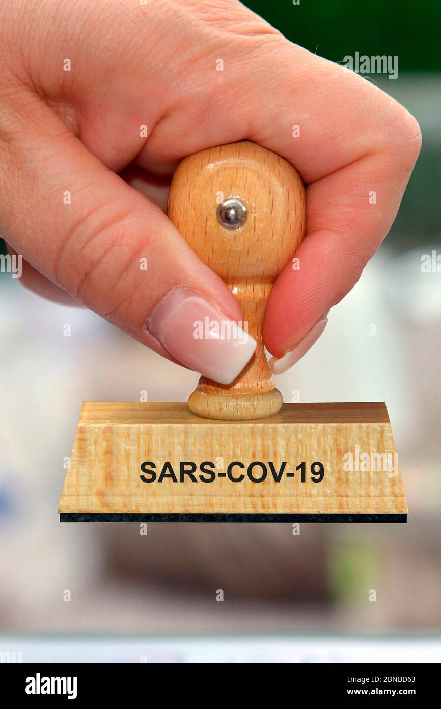 Timbro in mano di una donna scritta SARS COV-19, Germania Foto Stock