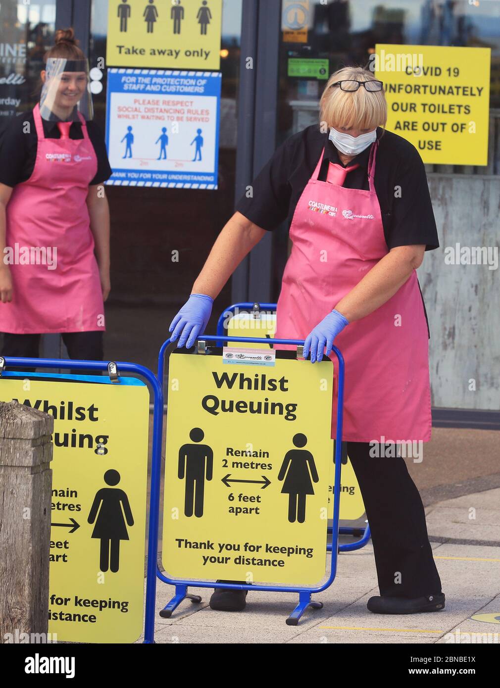 Il personale del negozio di pesce e patatine e della gelateria sulla spiaggia di Blyth, Northumberland, indossa i dispositivi di protezione individuale (PPE) mentre mettono i cartelli di allontanamento sociale per i clienti. Il ristorante ha riaperto per ordini di take away dopo l'allentamento delle restrizioni di blocco durante la pandemia del coronavirus. Foto Stock