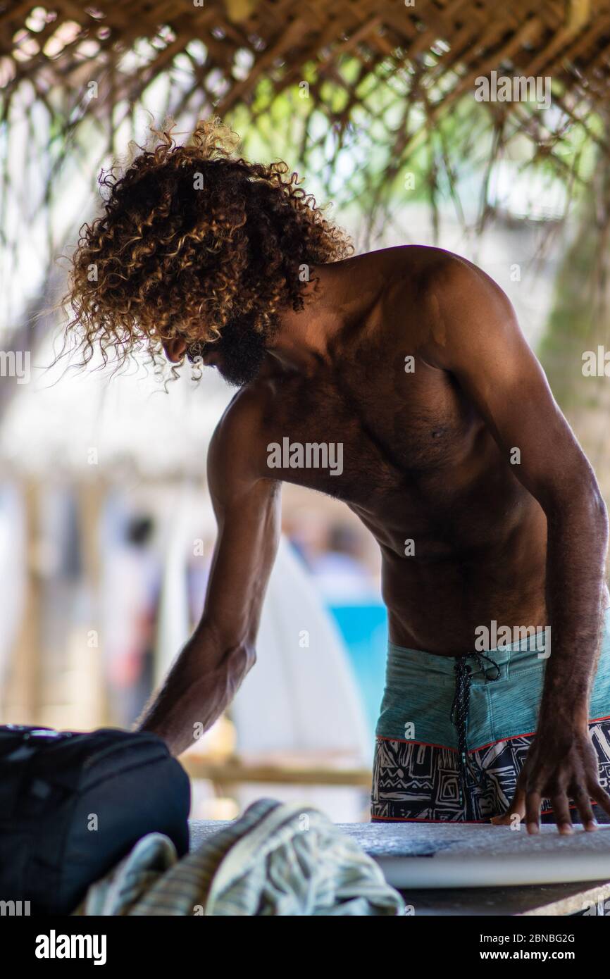 Surfer che ceretta la tavola da surf prima di pagaiare fuori a Hikkaduwa, Sri Lanka Foto Stock