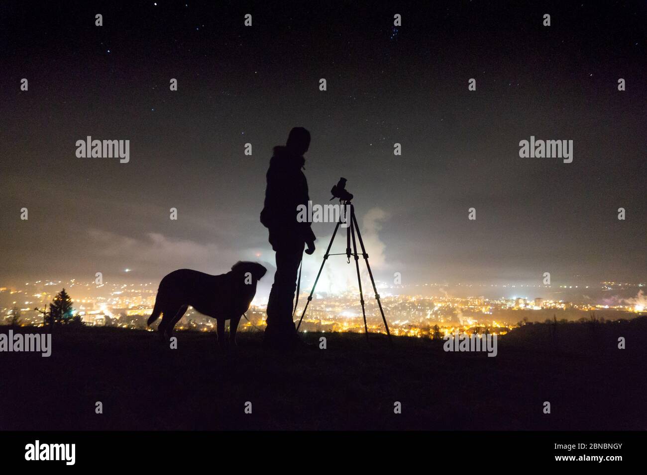 Silhouette di un uomo un cane e una macchina fotografica a. notte Foto Stock