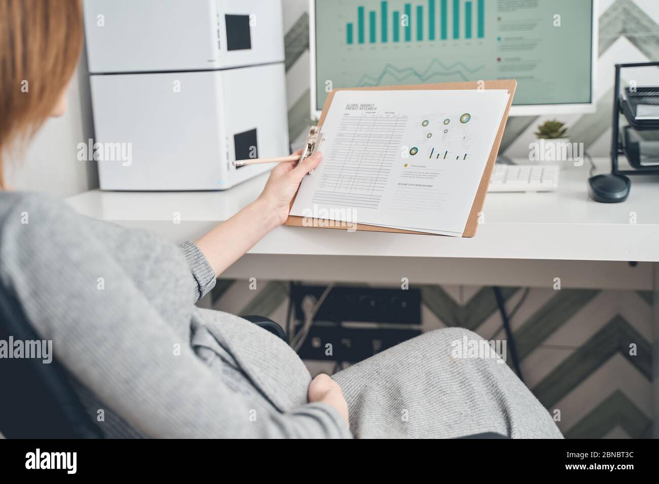 Donna incinta che detiene i risultati della ricerca globale di mercato energetico Foto Stock