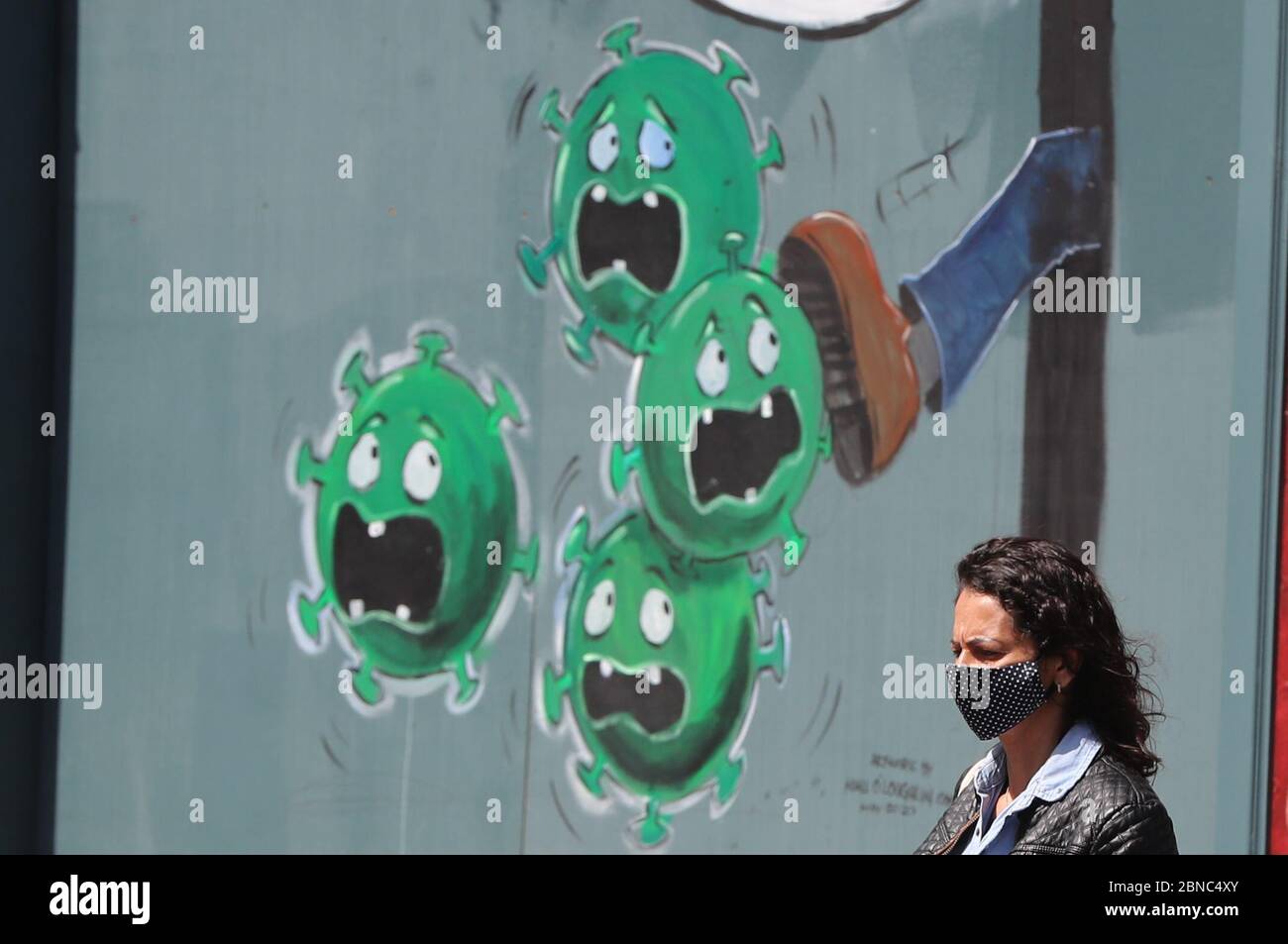 Una donna cammina davanti a un murale di coronavirus fuori dal Devitts Pub su Camden Street, Dublino. Foto Stock