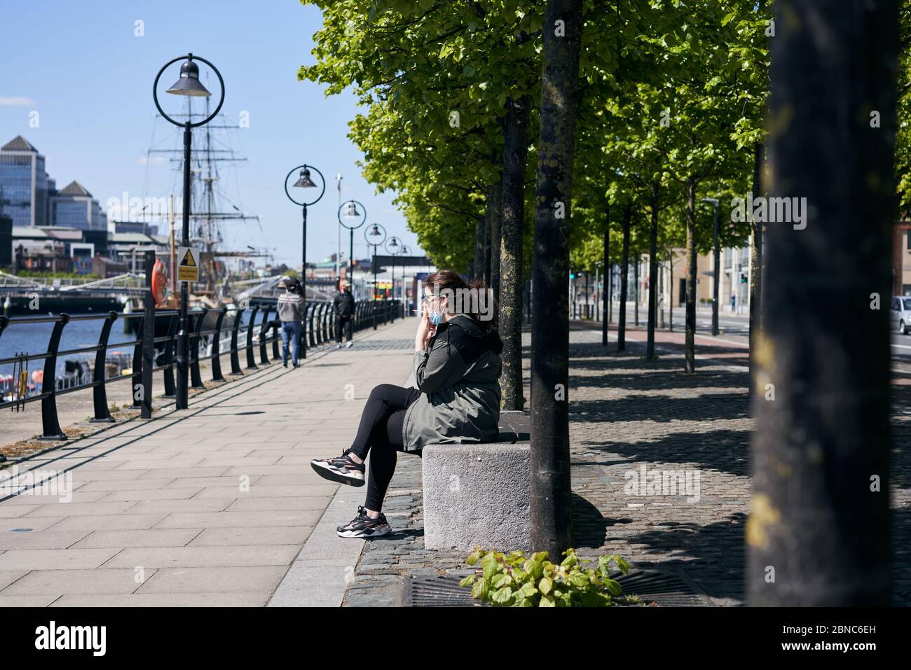 Una ragazza che fuma mentre indossa un maschera durante la pandemia globale del coronavirus nella città di Dublino, Irlanda. Foto Stock