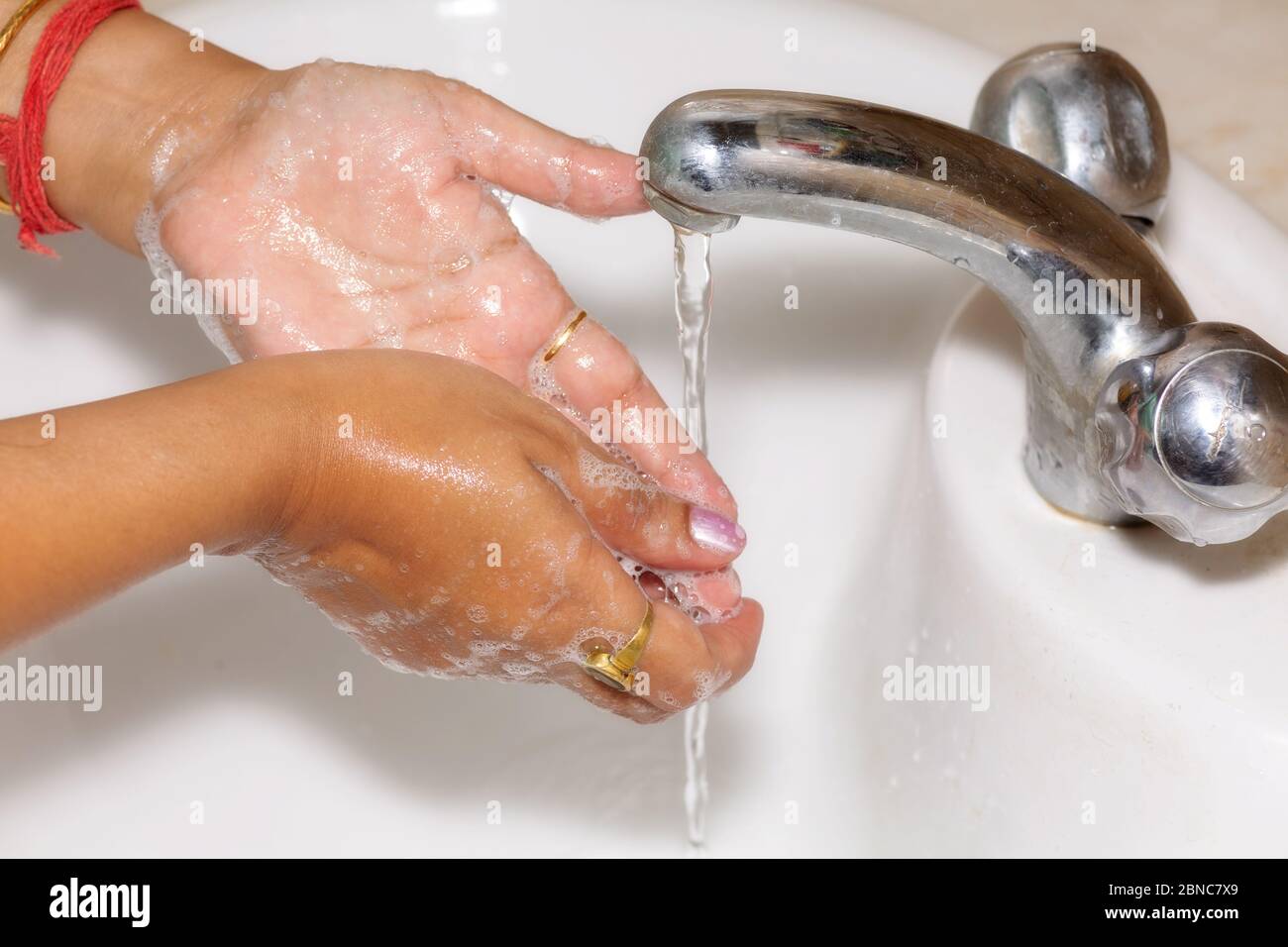Donna indiana lavando le mani con sapone per l'igiene come la consapevolezza preventiva del virus corona Foto Stock